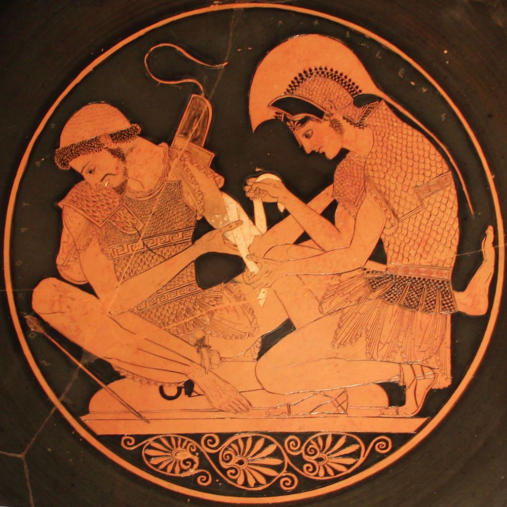 »Sosias-Schale«: Achilles verbindet den verwundeten Patroklos. Der in der Sitzstellung nach oben gerutschte Oberkörper-Panzer gibt den Blick auf das Geschlecht frei. Wikimedia, Lizenz Creative Commons »Sosias-Schale«: Achilles verbindet den verwundeten Patroklos. Der in der Sitzstellung nach oben gerutschte Oberkörper-Panzer gibt den Blick auf das Geschlecht frei. Wikimedia, Lizenz Creative Commons